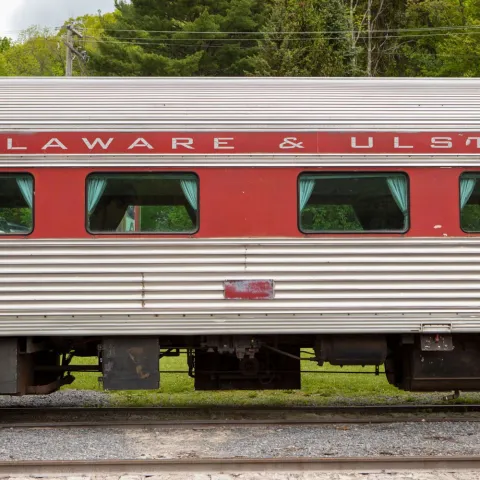Side view of a Delaware & Ulster train car with red and grey colors.